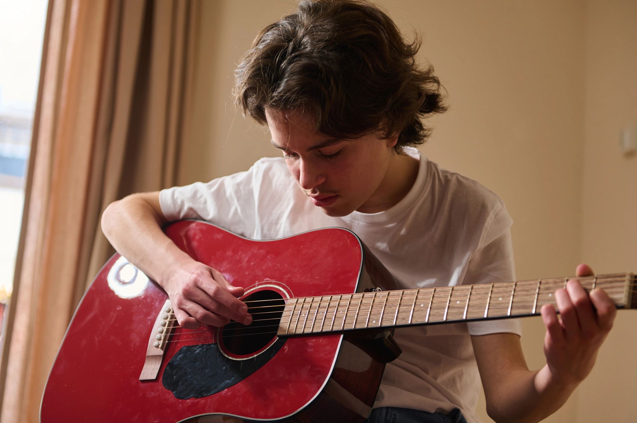 Teen practicing acoustic guitar during a lesson